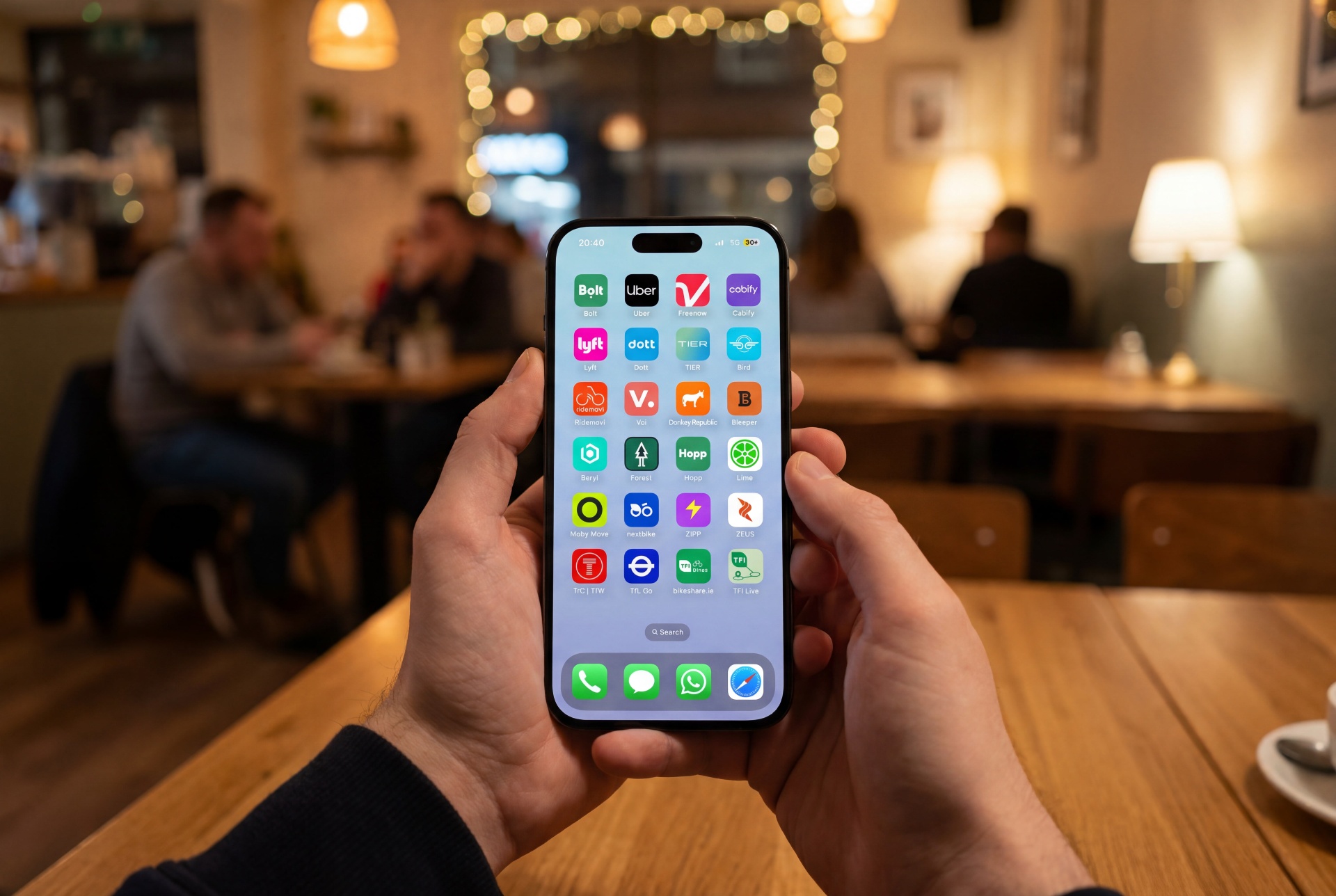 Hands holding a phone showing many transport apps in a cafe